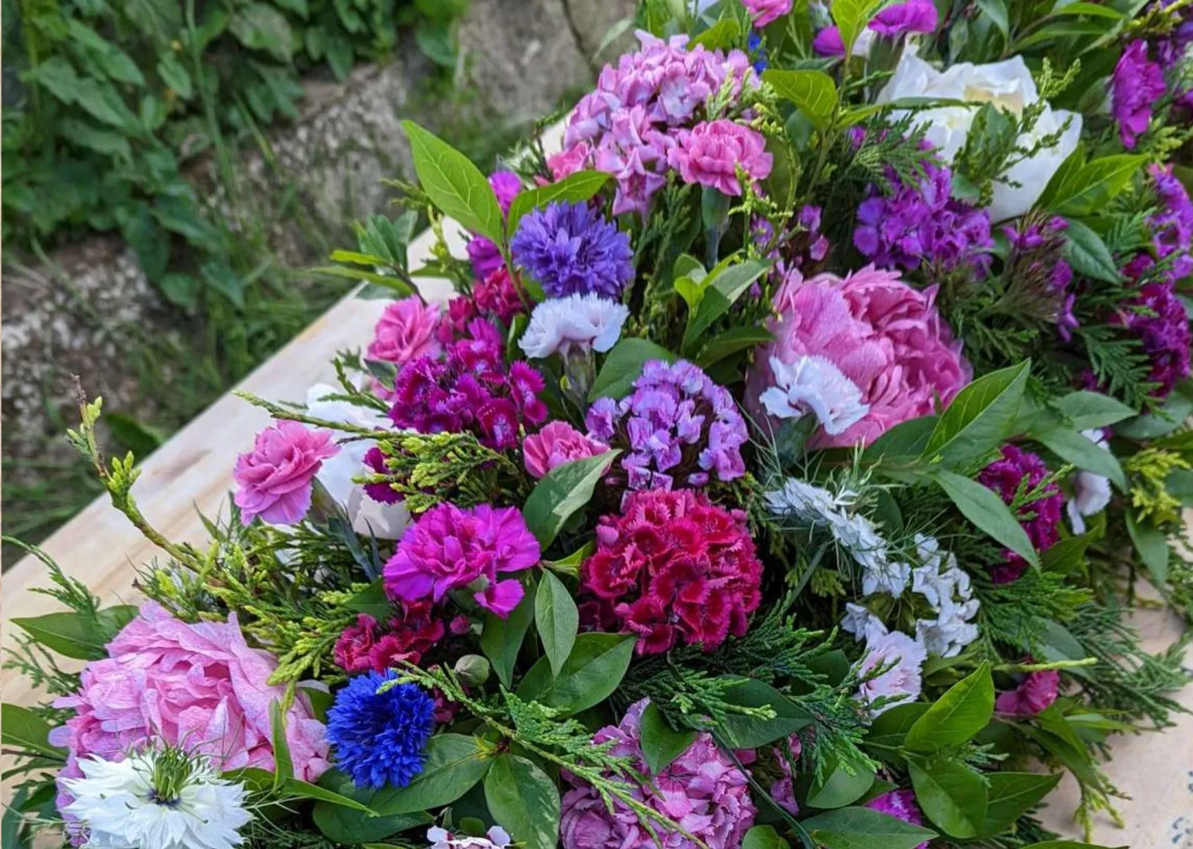 A full casket spray of pink, purple and white British flowers