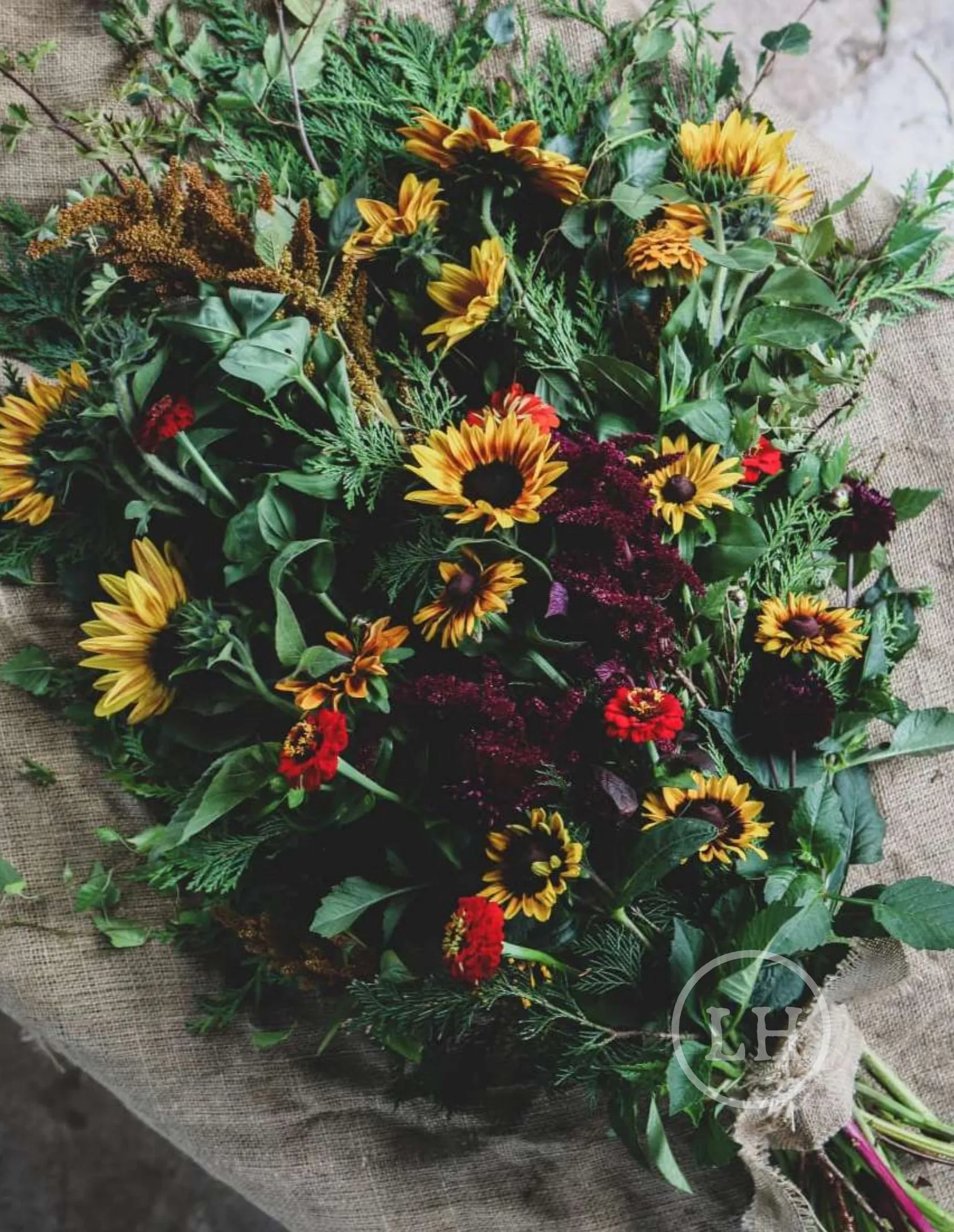 A sunflower and foliage funeral sheaf tied on hessian