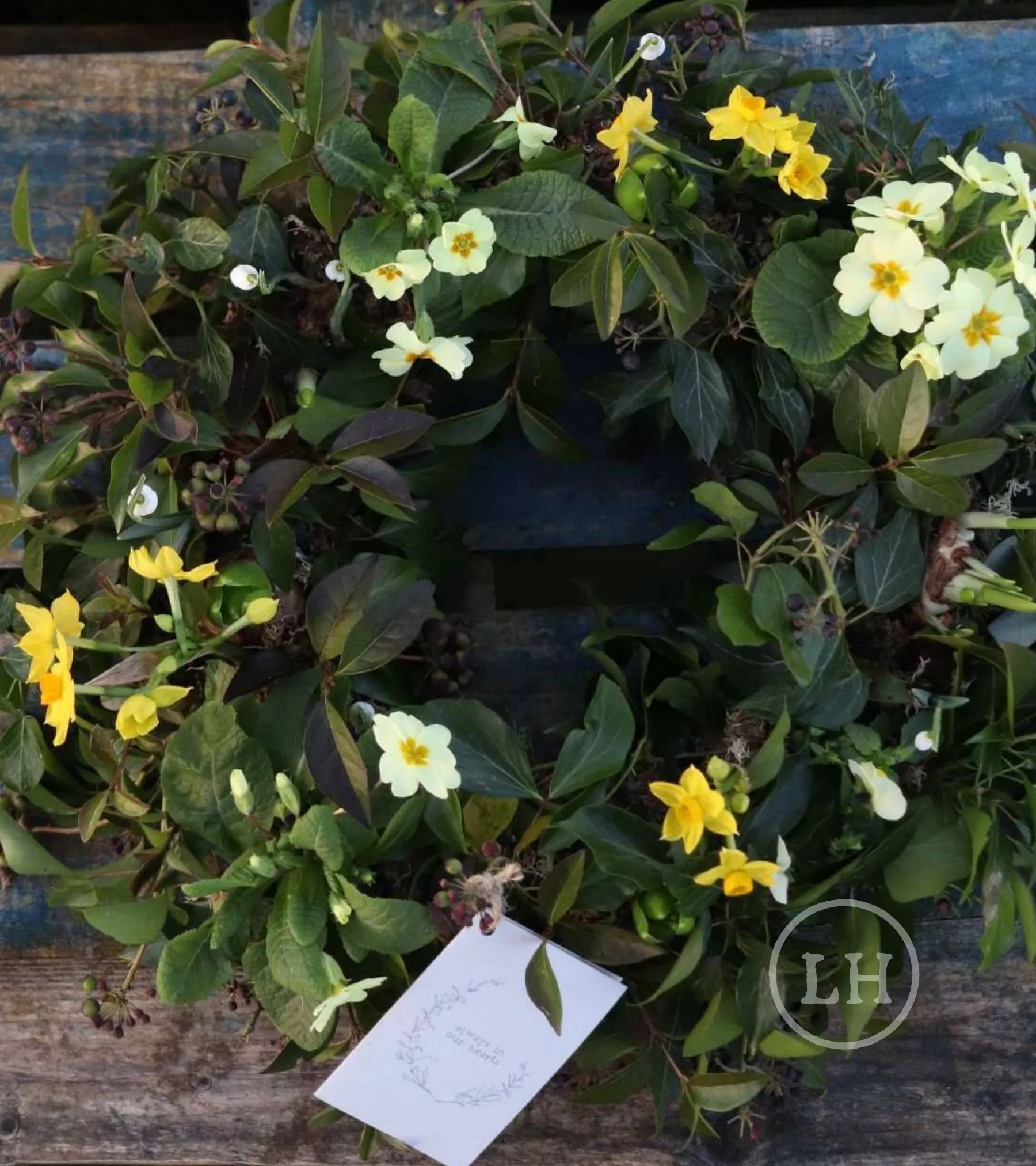 A compostable spring farewell wreath of primroses, daffodils and foliage